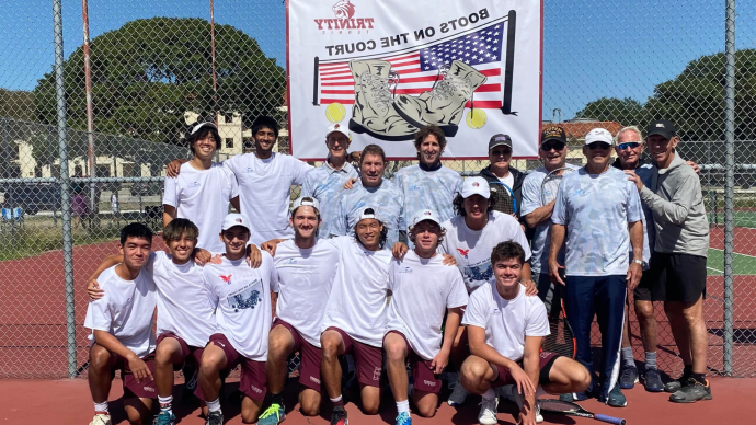 Current Trinity tennis players and alumni pose for a photo on a tennis court