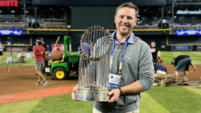 Stosh Hoover holding the World Series trophy while standing on a baseball field